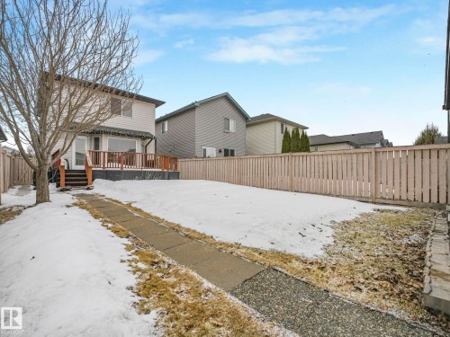The property features a large yard with a wooden deck, a paved walkway, and a wooden privacy fence - 21360 88 Avenue, Edmonton, AB - Outdoor With Deck Patio Veranda