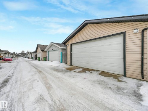 The property features a garage with a white overhead door and beige siding - 21360 88 Avenue, Edmonton, AB - Outdoor