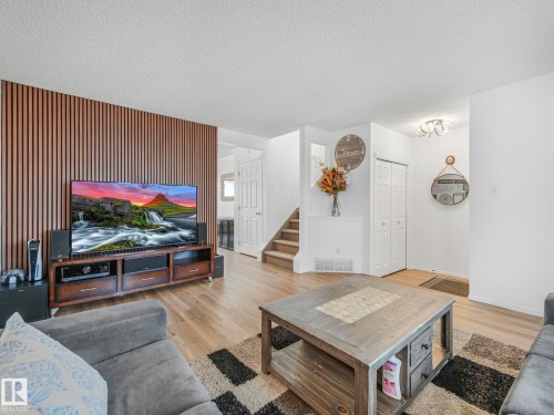 The living area features light wood flooring and a distinctive slatted accent wall - 21360 88 Avenue, Edmonton, AB - Indoor Photo Showing Living Room