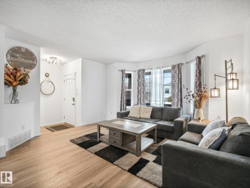 Living area featuring light wood flooring, a decorative area rug, and a bay window with curtains - 21360 88 Avenue, Edmonton, AB - Indoor Photo Showing Living Room
