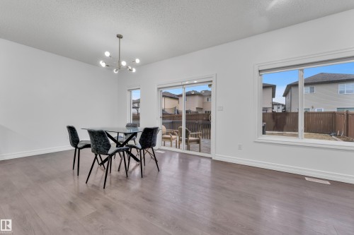Open-concept room featuring wood-finish flooring, white baseboards, and a modern chandelier - 3235 13 Avenue, Edmonton, AB - Indoor