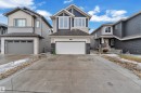 Contemporary two-story home featuring a dark blue and light tan siding exterior, a white garage door, and a stone facade accent - 3235 13 Avenue, Edmonton, AB  - Outdoor With Facade 