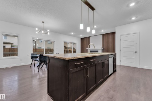 Kitchen island with a granite countertop, undermount sink, and dark wood cabinetry - 3235 13 Avenue, Edmonton, AB - Indoor Photo Showing Kitchen