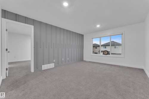Spacious room featuring gray carpet flooring, recessed lighting, and a prominent accent wall with vertical paneling - 3235 13 Avenue, Edmonton, AB - Indoor
