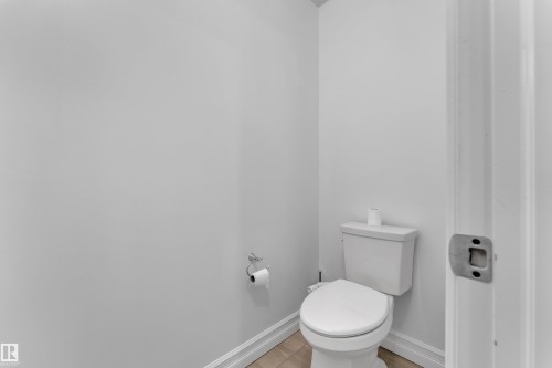 White toilet with a round bowl, tile flooring, light gray walls, and white baseboard trim - 3235 13 Avenue, Edmonton, AB - Indoor Photo Showing Bathroom