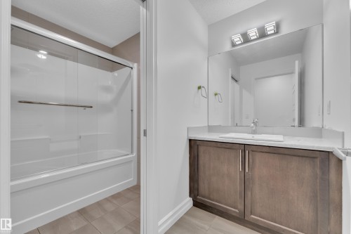 Bathroom vanity featuring a rectangular undermount sink, light-toned countertop, and wood-finish cabinetry - 3235 13 Avenue, Edmonton, AB - Indoor Photo Showing Bathroom