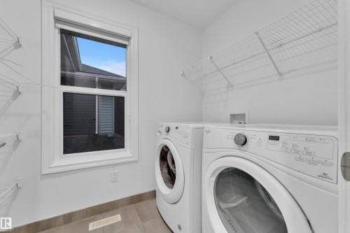 Laundry area featuring light-toned walls, tile flooring, a window with white trim, and wire shelving - 3235 13 Avenue, Edmonton, AB - Indoor Photo Showing Laundry Room