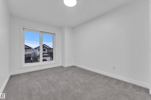 Room featuring a large window, neutral gray carpeting, white baseboards, white walls, and a flush mount ceiling light fixture - 3235 13 Avenue, Edmonton, AB - Indoor Photo Showing Other Room