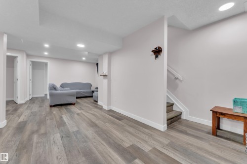 Spacious lower level featuring wood-finish flooring, recessed lighting, and white baseboards - 3235 13 Avenue, Edmonton, AB - Indoor