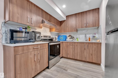Modern kitchen featuring wood-finish cabinetry, light countertops, and a subway tile backsplash - 3235 13 Avenue, Edmonton, AB - Indoor Photo Showing Kitchen