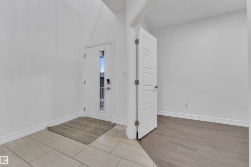 Entryway featuring light-toned tile flooring, a white door with a vertical window pane, and a contemporary handle set - 3235 13 Avenue, Edmonton, AB - Indoor Photo Showing Other Room