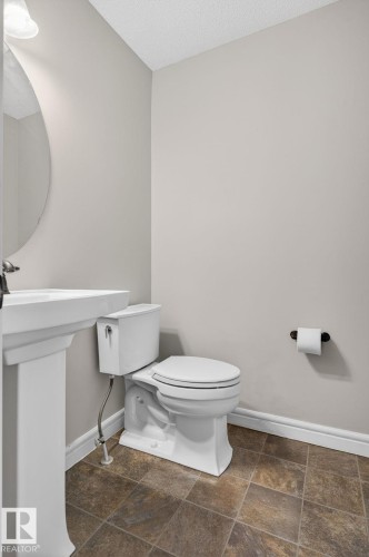 Bathroom featuring a white pedestal sink, classic white toilet, and square tile flooring - 332 Nelson Drive, Spruce Grove, AB - Indoor Photo Showing Bathroom