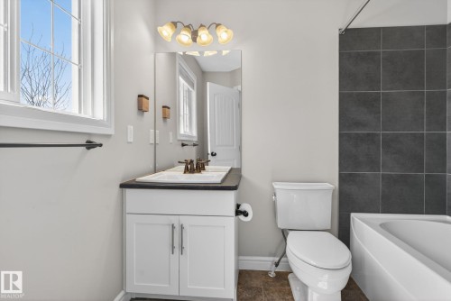 Bathroom featuring a white vanity with dual sinks, a dark countertop, and brushed bronze fixtures - 332 Nelson Drive, Spruce Grove, AB - Indoor Photo Showing Bathroom