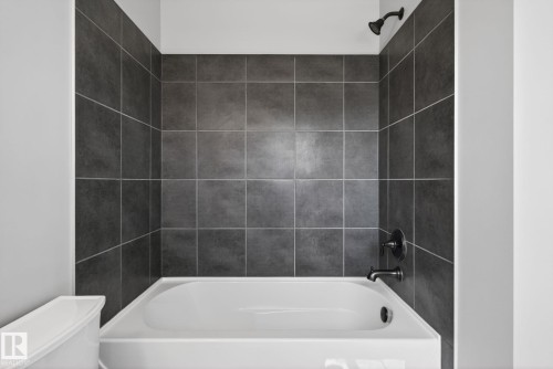 Bathroom featuring a white tub, dark gray tiled shower surround, and oil-rubbed bronze fixtures - 332 Nelson Drive, Spruce Grove, AB - Indoor Photo Showing Bathroom
