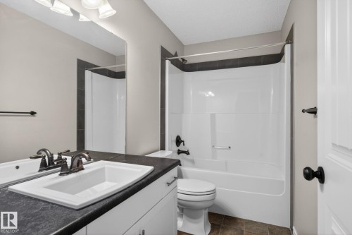 Bathroom featuring a white vanity with an integrated sink, dark countertop, and brushed bronze faucet - 332 Nelson Drive, Spruce Grove, AB - Indoor Photo Showing Bathroom