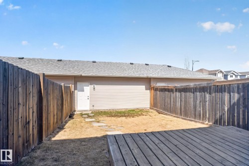 Expansive backyard featuring a wood deck, perimeter wood fencing, and a side-entry door - 332 Nelson Drive, Spruce Grove, AB - Outdoor With Deck Patio Veranda With Exterior