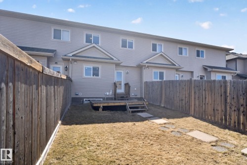 Private backyard with a wooden fence, featuring a raised deck with stairs, a patio door, and a stone paver pathway - 332 Nelson Drive, Spruce Grove, AB - Outdoor