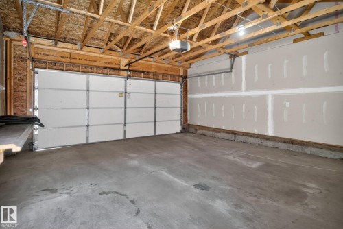 Spacious garage featuring a concrete floor, exposed wood ceiling joists, and an automatic garage door opener - 332 Nelson Drive, Spruce Grove, AB - Indoor Photo Showing Garage