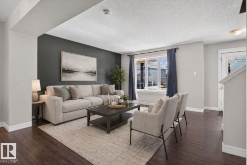 Living area featuring laminate finish flooring, a contemporary accent wall, a large window with natural light - 332 Nelson Drive, Spruce Grove, AB - Indoor Photo Showing Living Room