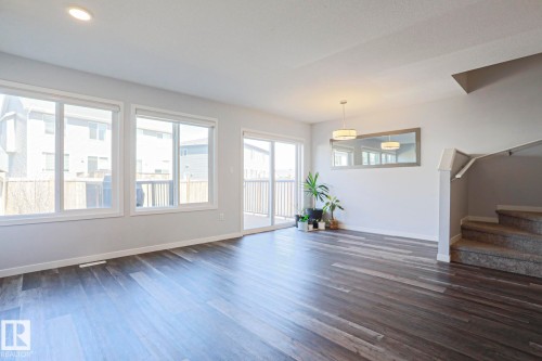 Spacious interior featuring wood-finish flooring, ample natural light from multiple windows, and a sliding glass door to an outdoor deck - 4314 Cooke Lane, Edmonton, AB - Indoor Photo Showing Other Room