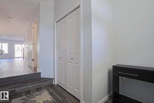Entryway featuring wood-finish flooring, white bifold closet doors, and light neutral wall paint - 4314 Cooke Lane, Edmonton, AB - Indoor Photo Showing Other Room