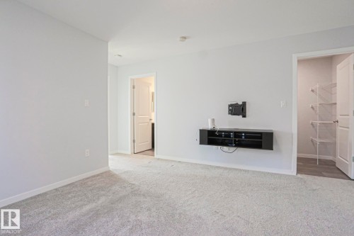 Wall-to-wall carpeting in a neutral tone complements light gray walls, offering a bright interior - 4314 Cooke Lane, Edmonton, AB - Indoor Photo Showing Other Room