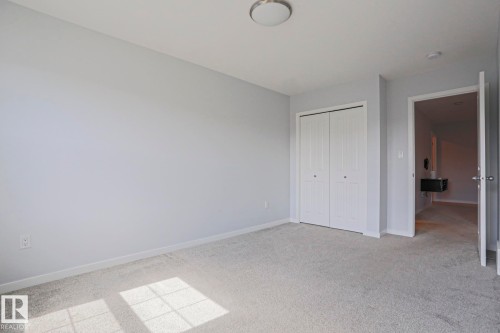 Spacious room featuring light gray wall paint, light-colored carpet flooring, a flush-mount ceiling light fixture, and bi-fold closet doors - 4314 Cooke Lane, Edmonton, AB - Indoor