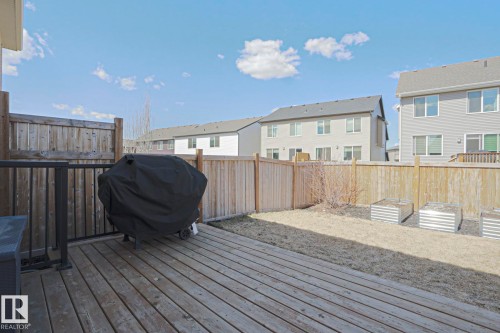 Spacious backyard featuring a wooden deck, privacy fencing, and galvanized steel garden beds - 4314 Cooke Lane, Edmonton, AB - Outdoor With Exterior