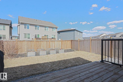 Spacious backyard featuring wood fencing, a wood deck with black metal railing, and four raised garden beds - 4314 Cooke Lane, Edmonton, AB - Outdoor