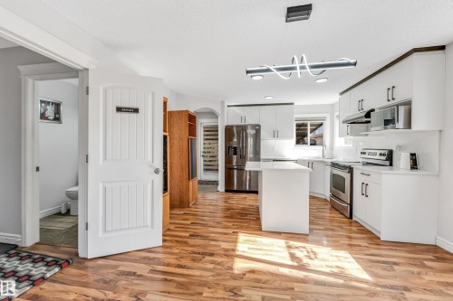 Kitchen featuring white cabinetry, stainless steel appliances, a center island, wood-finish flooring, and recessed lighting - 1921 119A Street, Edmonton, AB - Indoor Photo Showing Kitchen With Upgraded Kitchen