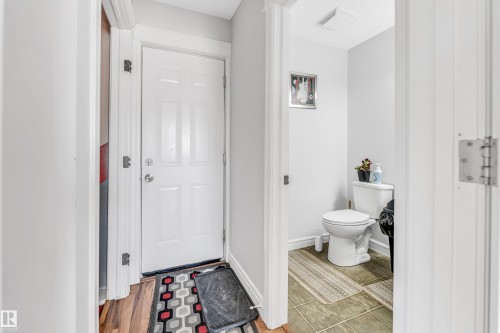 Entryway featuring a paneled door with polished hardware, wood-finish flooring, and light gray wall paint - 1921 119A Street, Edmonton, AB - Indoor Photo Showing Bathroom