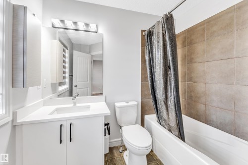 Full bathroom featuring a white vanity with an integrated sink, a large mirror, and a contemporary light fixture - 1921 119A Street, Edmonton, AB - Indoor Photo Showing Bathroom