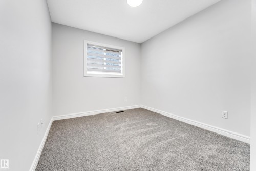 Neutral gray wall paint, gray carpet, white baseboards, white window trim, and a flush-mount ceiling light fixture - 1921 119A Street, Edmonton, AB - Indoor Photo Showing Other Room