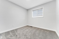 Room featuring light gray wall paint, gray patterned carpet, white baseboards, and a window with horizontal blinds - 