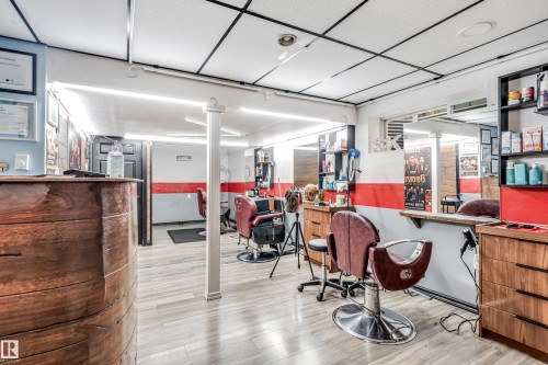 Commercial space featuring wood-finish flooring, a wood-paneled reception desk, suspended ceiling, and recessed lighting - 1921 119A Street, Edmonton, AB - Indoor