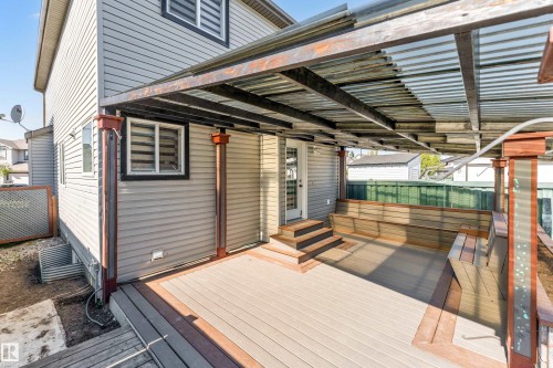 Covered outdoor deck featuring built-in bench seating, durable composite decking, and a corrugated metal roof - 1921 119A Street, Edmonton, AB - Outdoor With Deck Patio Veranda With Exterior
