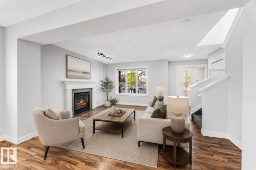 Living area with wood-finish flooring, a white mantel fireplace, and track lighting - 1921 119A Street, Edmonton, AB - Indoor Photo Showing Living Room With Fireplace