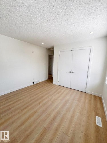 Bright interior room with wood-finish flooring, recessed lighting, white walls, and built-in double closet doors - 20 Hunt Road, Edmonton, AB - Indoor Photo Showing Other Room