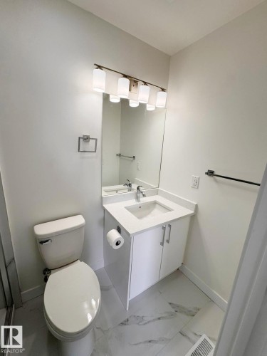 Bathroom featuring a white vanity with an integrated sink, polished chrome faucet, and white countertop - 20 Hunt Road, Edmonton, AB - Indoor Photo Showing Bathroom