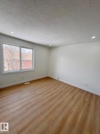 Spacious room featuring wood-finish flooring, white baseboards, and white walls - 