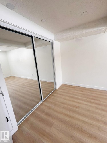 Spacious room featuring mirrored closet doors, recessed lighting, white baseboards, and wood-finish flooring - 20 Hunt Road, Edmonton, AB - Indoor Photo Showing Other Room