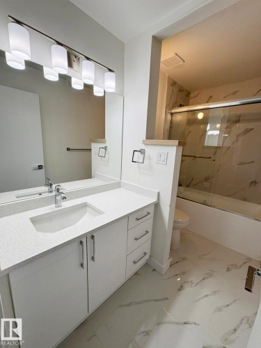 Contemporary bathroom featuring a white vanity with integrated sink, quartz-finish countertop, and chrome fixtures - 20 Hunt Road, Edmonton, AB - Indoor Photo Showing Laundry Room
