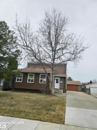 Brown siding exterior with white window frames and a white front door - 
