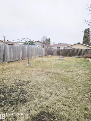 Expansive backyard featuring a full perimeter wooden fence, a clothesline, and a built-in fire pit - 20 Hunt Road, Edmonton, AB - Outdoor