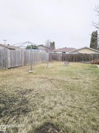 Expansive backyard featuring a full perimeter wooden fence, a clothesline, and a built-in fire pit - 