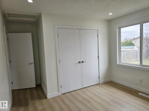 Bright room featuring wood-finish flooring, a large window, recessed lighting, white baseboards, and a double-door closet - 20 Hunt Road, Edmonton, AB - Indoor Photo Showing Other Room