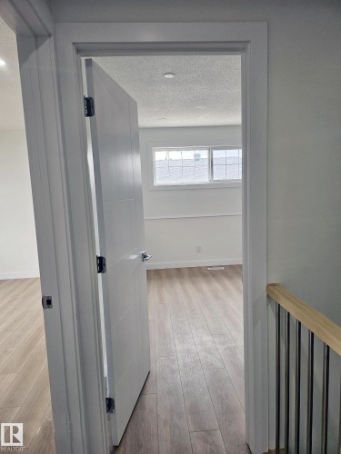 Interior room showcasing wood-finish flooring, white baseboards, and a window with horizontal muntins - 20 Hunt Road, Edmonton, AB - Indoor Photo Showing Other Room