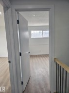 Interior room showcasing wood-finish flooring, white baseboards, and a window with horizontal muntins - 
