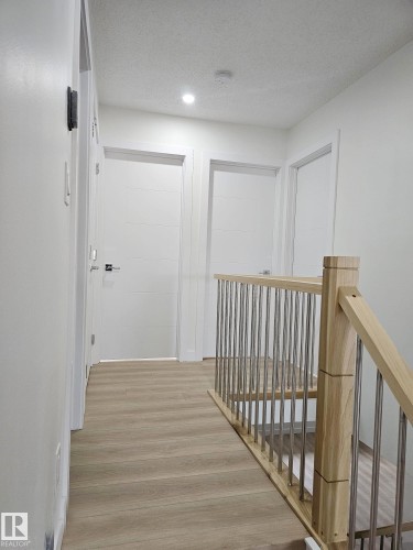 Upper-level hallway featuring wood-finish flooring, recessed lighting, and a contemporary wood and metal railing - 20 Hunt Road, Edmonton, AB - Indoor Photo Showing Other Room