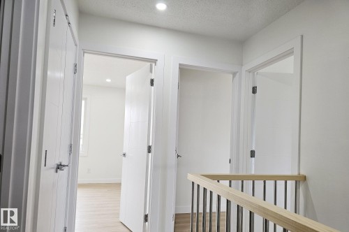 Bright hallway featuring a light wood railing with metal balusters, recessed lighting, and white paneled doors with chrome hardware - 20 Hunt Road, Edmonton, AB - Indoor Photo Showing Other Room